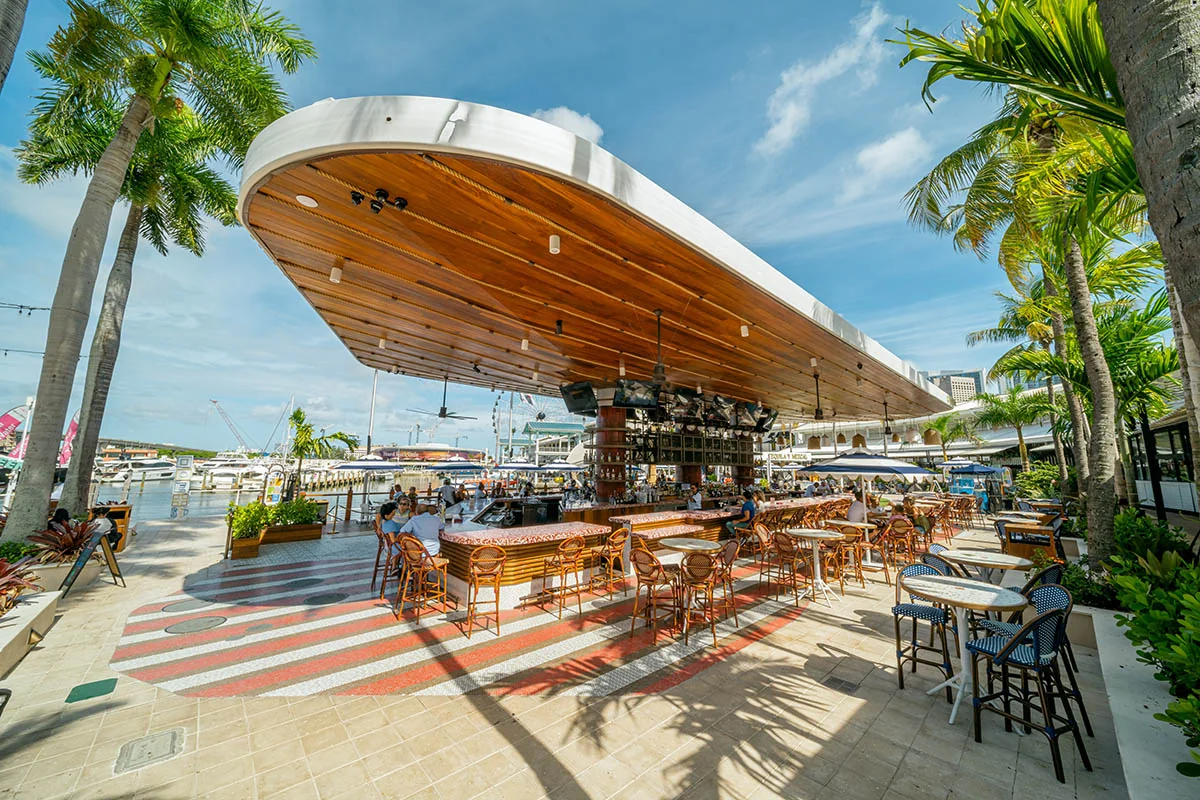 Pier 5’s curved canopy and open-air Rum Bar, with waterfront tables and palm trees