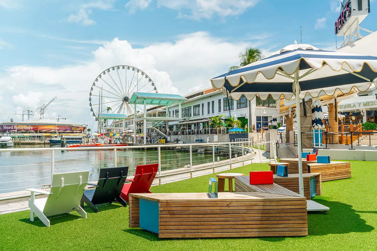Waterfront seating and lawn games at Pier 5, overlooking the Bayside Marketplace marina and observation wheel